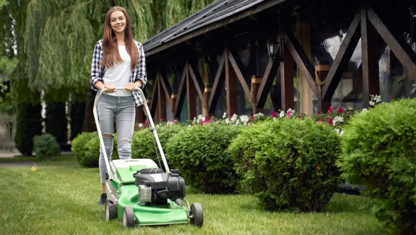 Young woman mowing a lawn