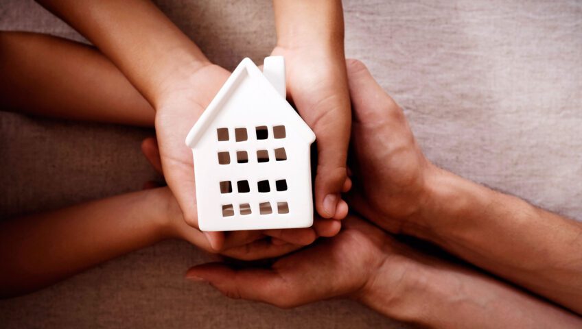 Hands holding a model of a house