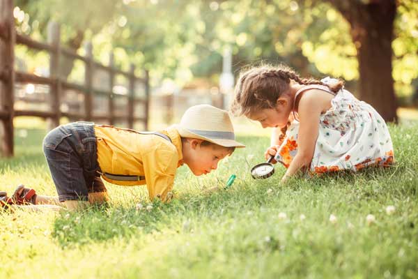 Two Children in Yard with Magnifying Glass